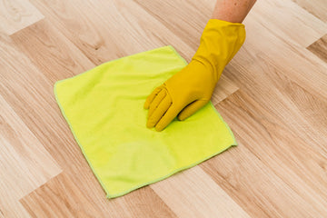 Homeowner cleaning engineered hardwood flooring with microfiber mop, highlighting natural oak wood grain.